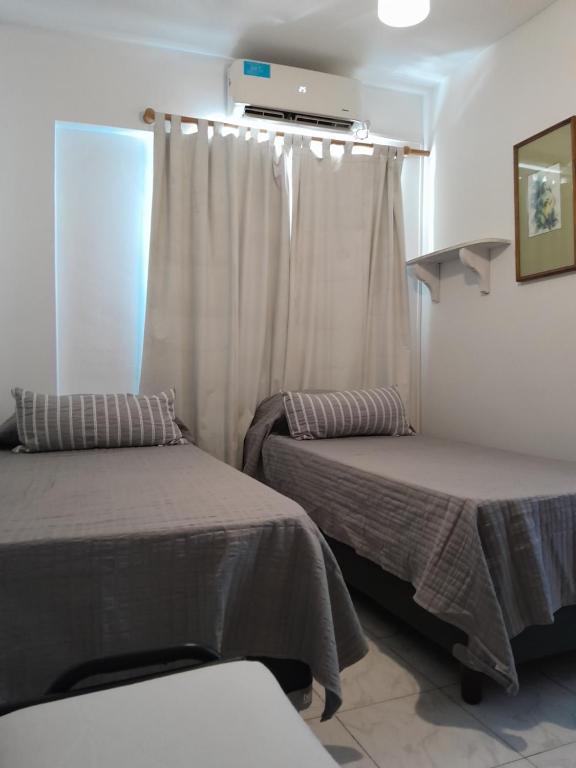 Habitación con 2 camas y ventana con cortinas. en Duplex Céntrico en Mendoza
