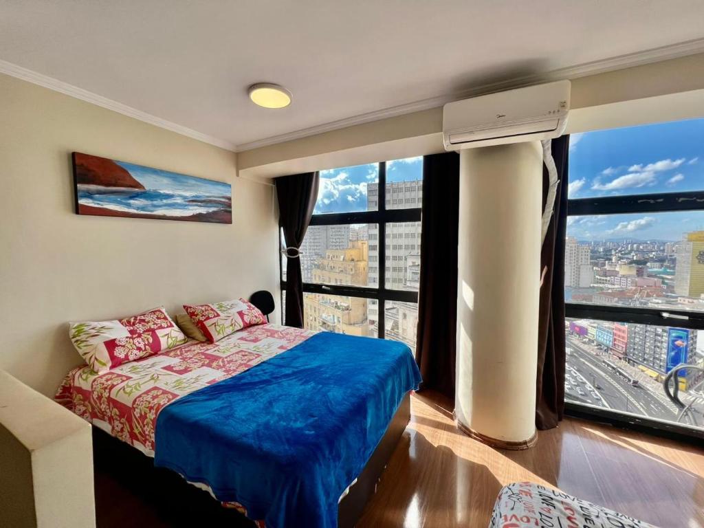 een slaapkamer met een bed en een groot raam bij Studio Aconchegante no Edifício Mirante do Vale - 200Mb in Sao Paulo
