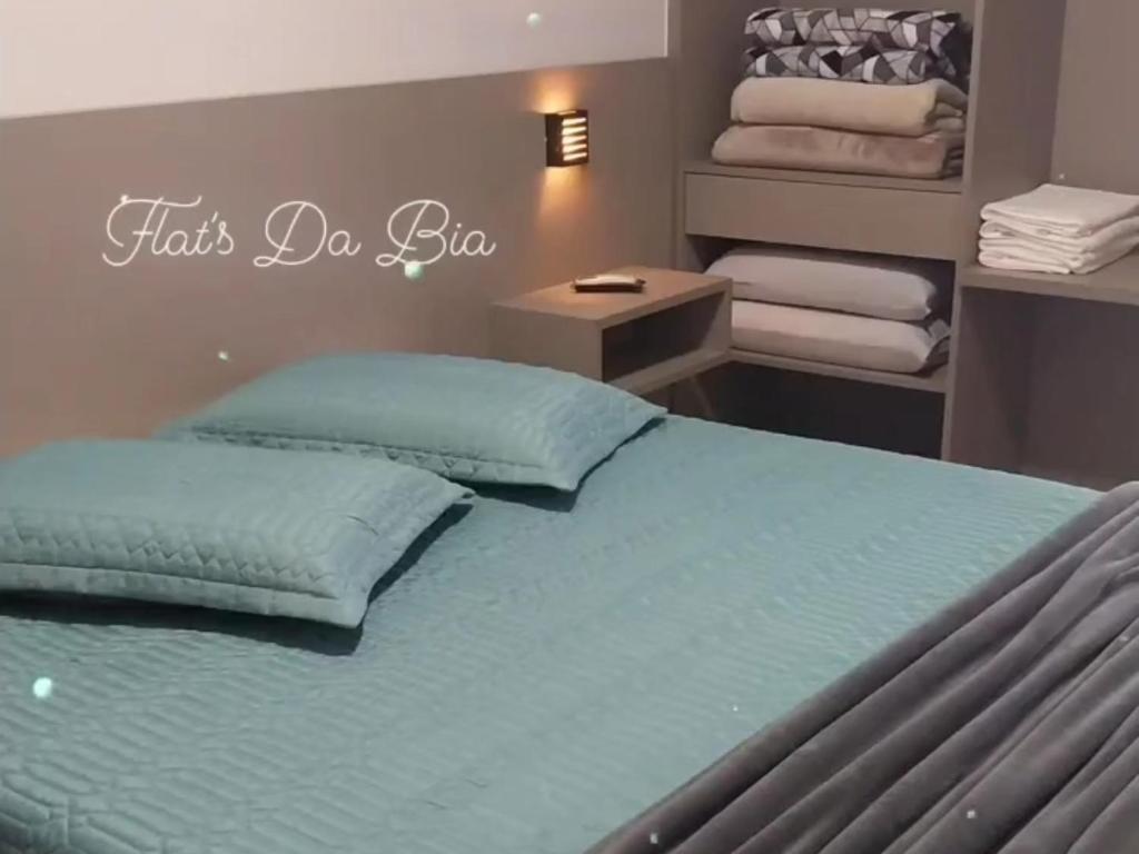 1 dormitorio con 1 cama con sábanas y almohadas azules en Flat's Da Bia, en Cananéia