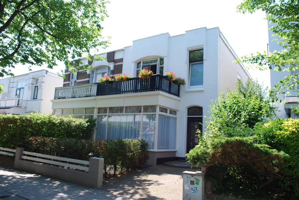 biały budynek z balkonem z kwiatami w obiekcie Picco Bello w Zandvoort