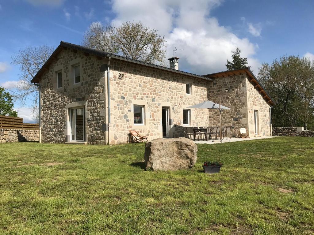 a stone house with a large rock in front of it at Charmante maison en pierre près du Lac de Lavalette, idéale pour randos, nature et détente totale - FR-1-582-43 in Saint-Jeures