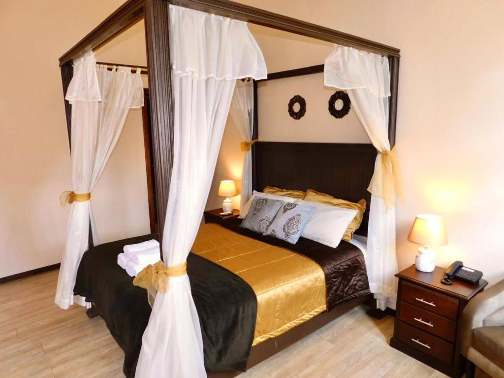 a bedroom with a canopy bed with white curtains at HOTEL en el CENTRO HISTORICO in Cuenca