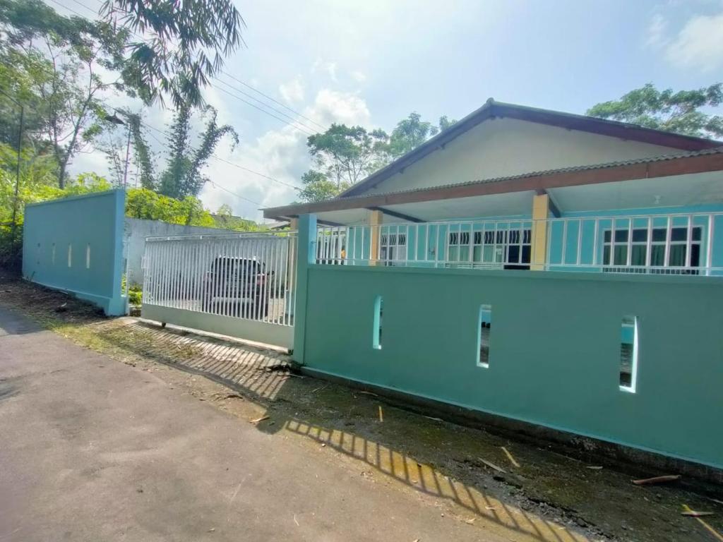 een blauw huis met een hek ervoor bij Hutama Kaliurang Guest House in Soprayan