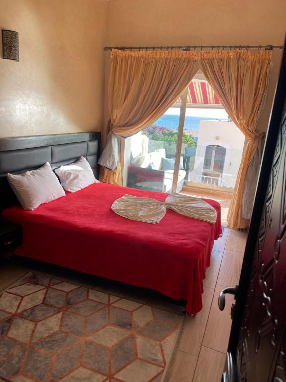 um quarto com uma cama com um cobertor vermelho e uma janela em Appartement vue sur mer em Agadir