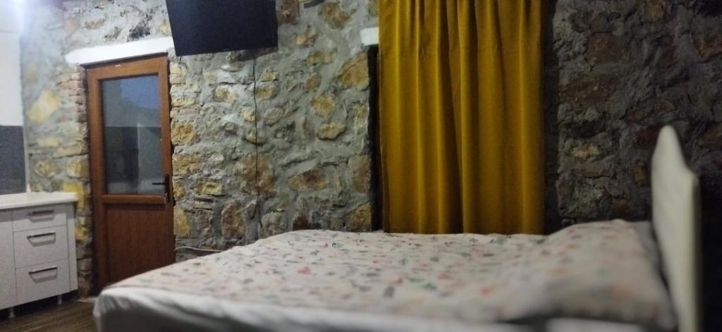 a bedroom with a bed and a stone wall at Su camping in Dağpınar