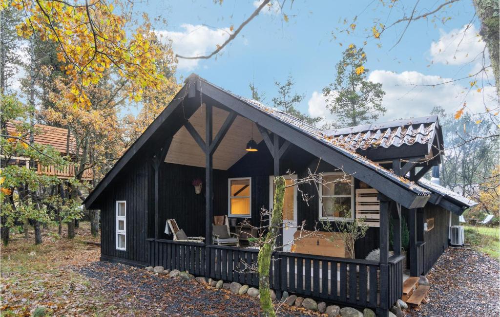 una pequeña casa negra en el bosque en Cozy Home In Oksbl With Kitchen, en Oksbøl