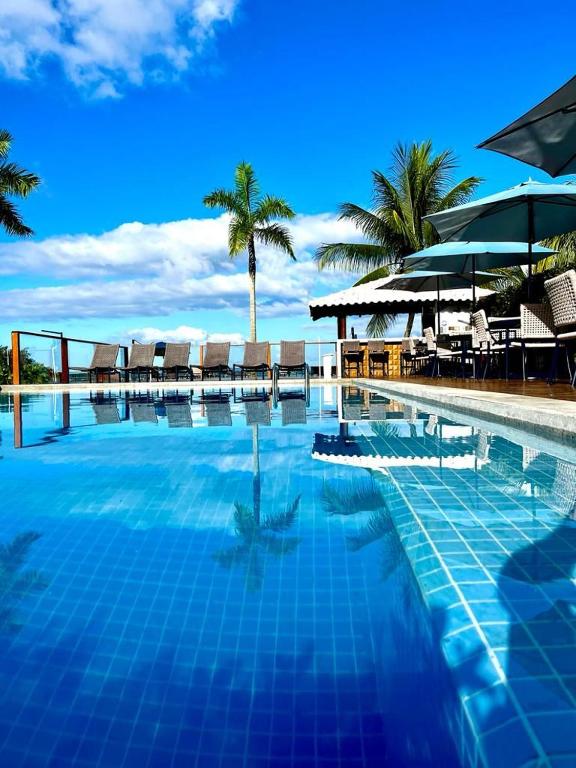 a swimming pool with chairs and umbrellas on a beach at Barra Grande Exclusive Residence in Barra Grande