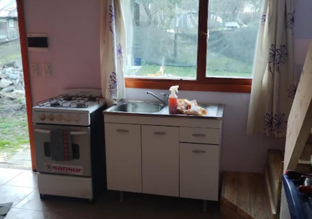 cocina con fregadero, fogones y ventana en La Casita del Oso en San Carlos de Bariloche