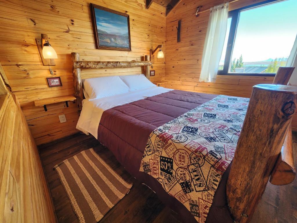 um quarto com uma cama num chalé de madeira em Cabañas Alechen em El Calafate