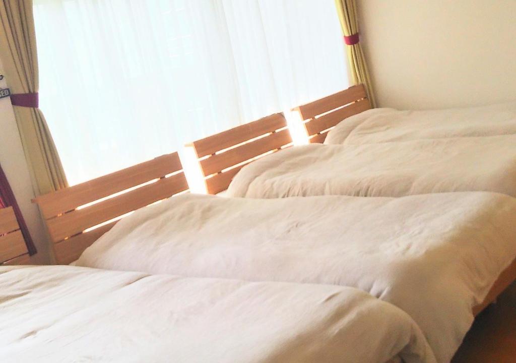 two twin beds in a room with a window at Guest House Nishikanazawa Smile & smile - Vacation STAY 12106v in Kanazawa