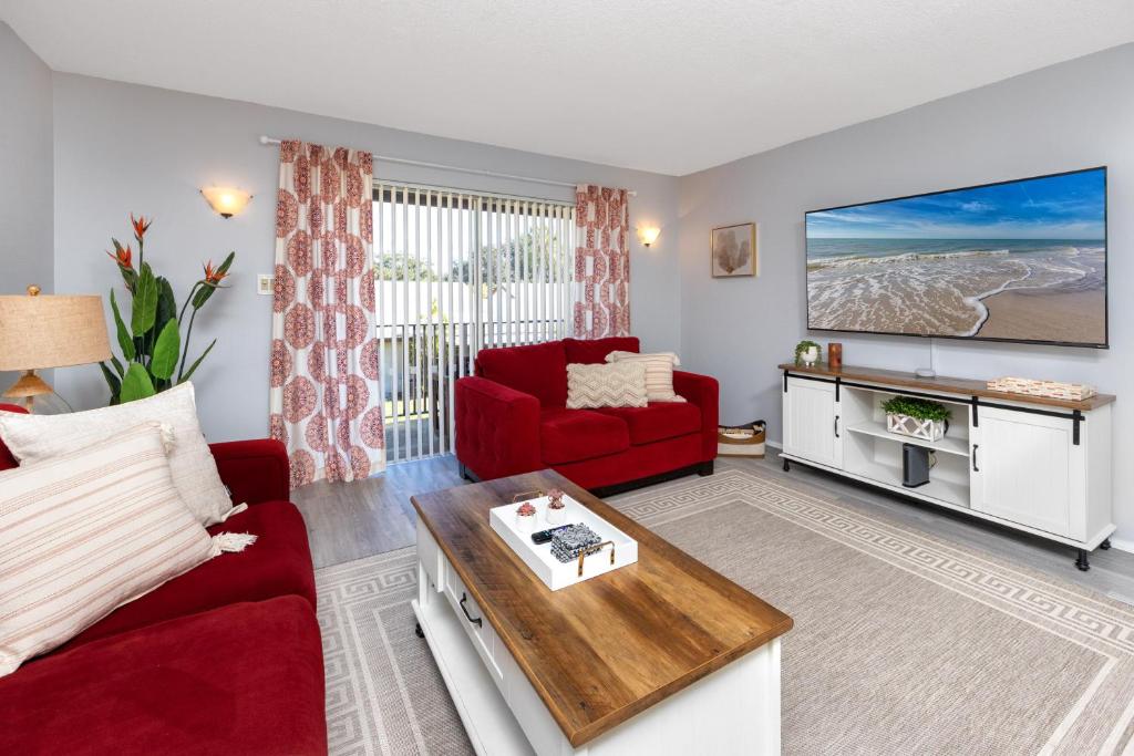 a living room with a red couch and a tv at Stylish Clearwater place. 3 Pools. Mins to Beaches in Clearwater