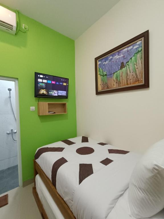 a bedroom with a bed and a television on the wall at The Cabin Hotel Sumberan in Yogyakarta