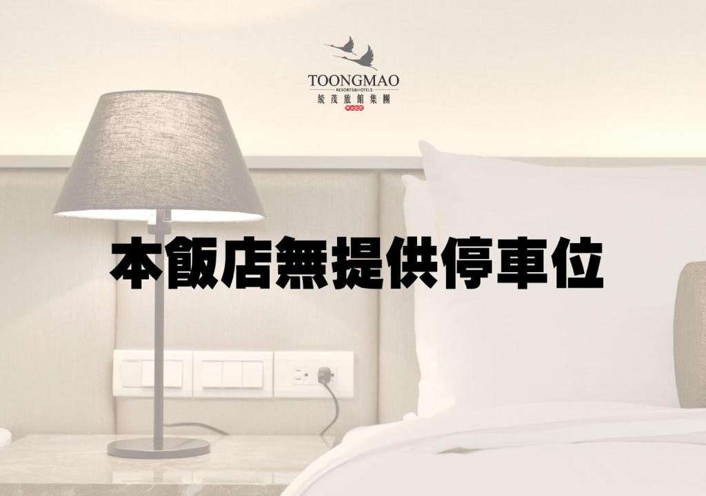 a bedroom with a lamp and a white bed at Toongmao Hotel Kaohsiung in Kaohsiung