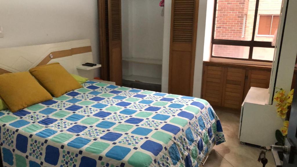 um quarto com uma cama com uma colcha azul e branca em LA SÚPER HABITACIÓN DE LA FRONTERA POBLADO / ENVIGADO em Envigado