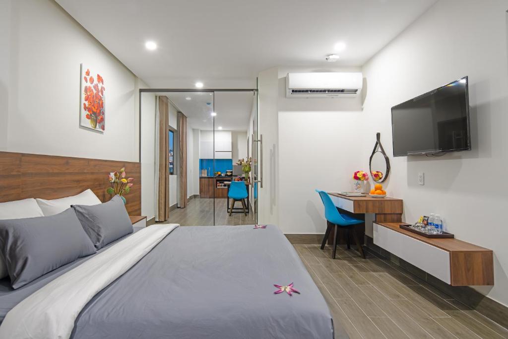 Schlafzimmer mit einem Bett, einem Schreibtisch und einem TV in der Unterkunft TIDITEL Hotel and Apartment in Đà Nẵng