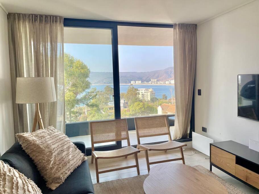 a living room with a couch and chairs and a large window at Departamento Papudo Nuevo! in Papudo