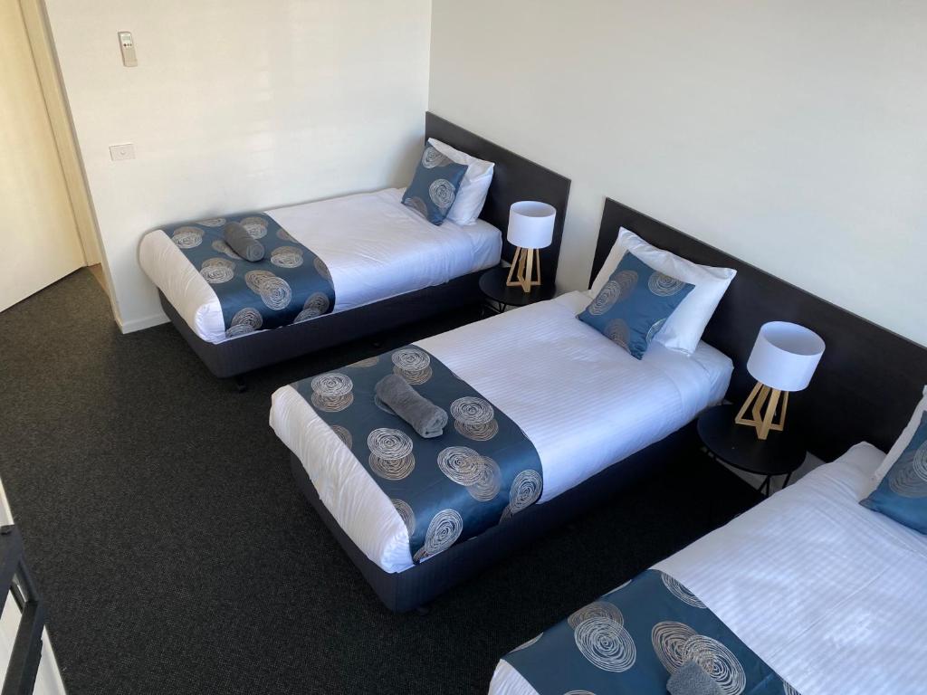 a room with three beds and two twin beds at Southern Ocean Motor Inn in Port Campbell