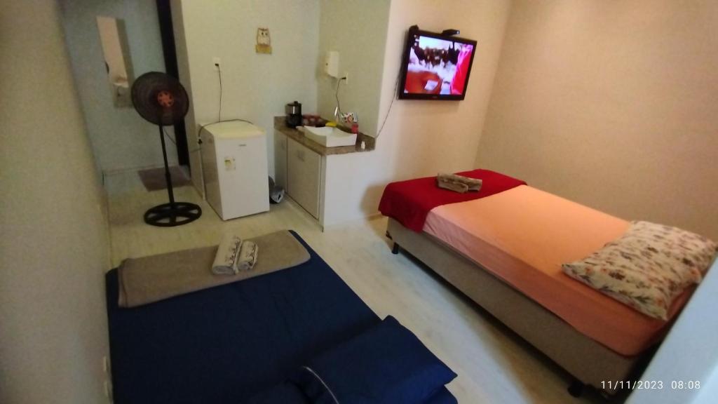 een kleine slaapkamer met een bed en een televisie bij Apartamento central particular in Lavras