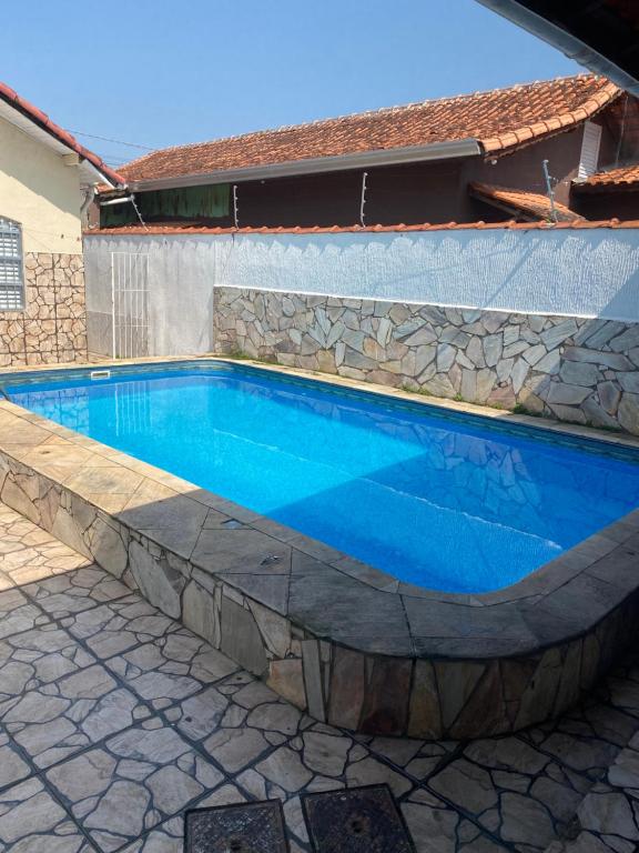 uma piscina com uma parede de pedra e água azul em Casa de praia com piscina em Solemar