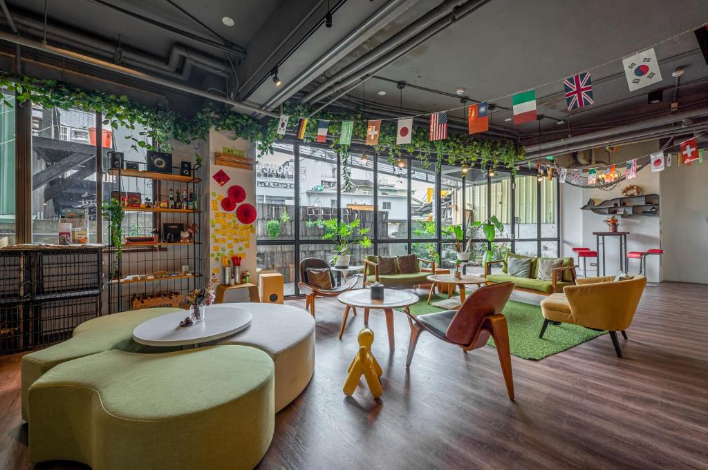 Light Hostel - Tainan في تاى نان: غرفة بها كراسي وطاولات وكراسي ونوافذ