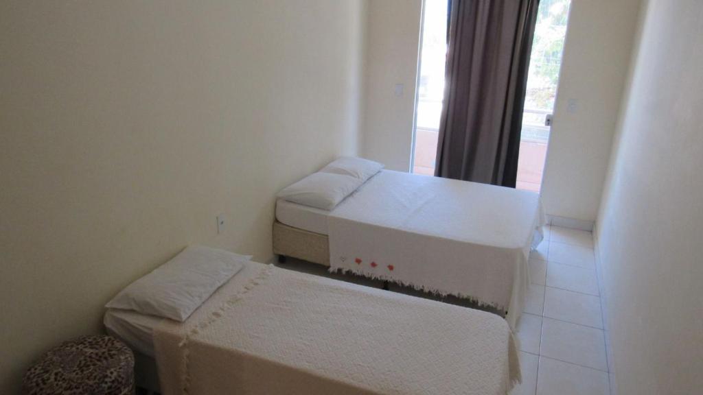 a small room with two beds and a window at Residencial Edite Bulhões in Guaibim