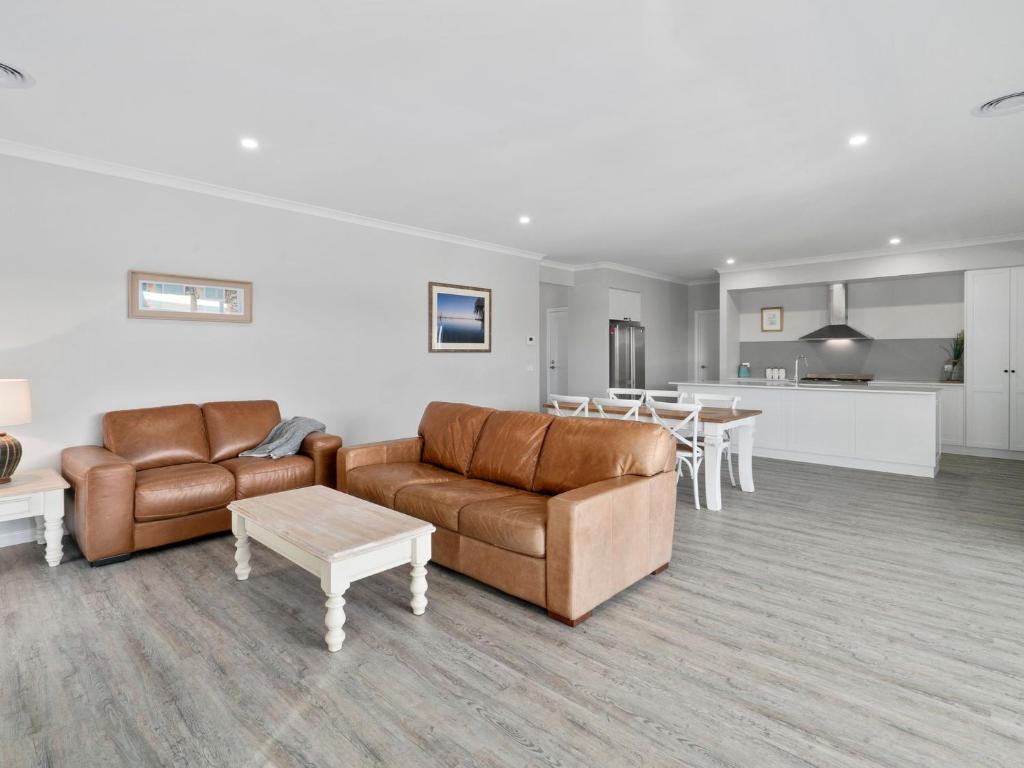 a living room with couches and tables and a kitchen at Sunsets by the Lake in Yarrawonga