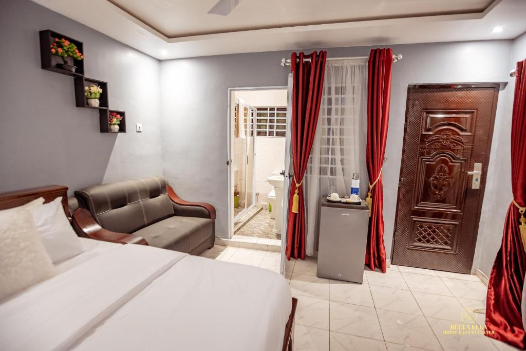 a bedroom with a bed and a chair and a bathroom at Bella Ella Hotel & Event Center in Kasoa