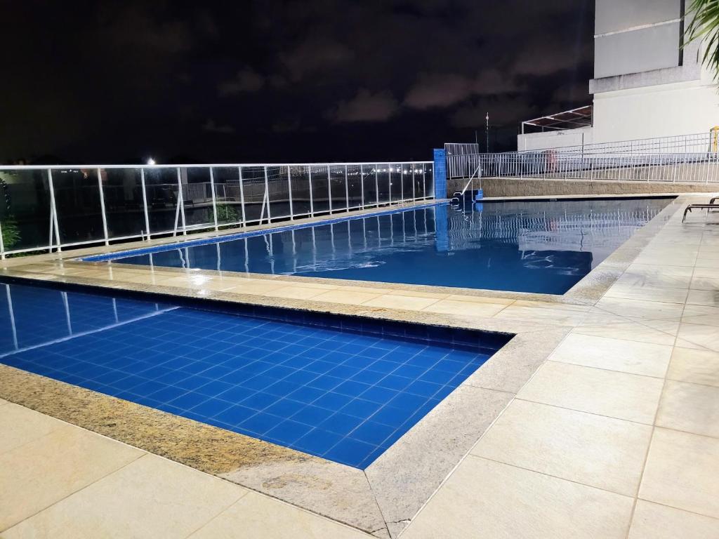 a swimming pool at night with blue water at Residencial Jardim da costa in João Pessoa