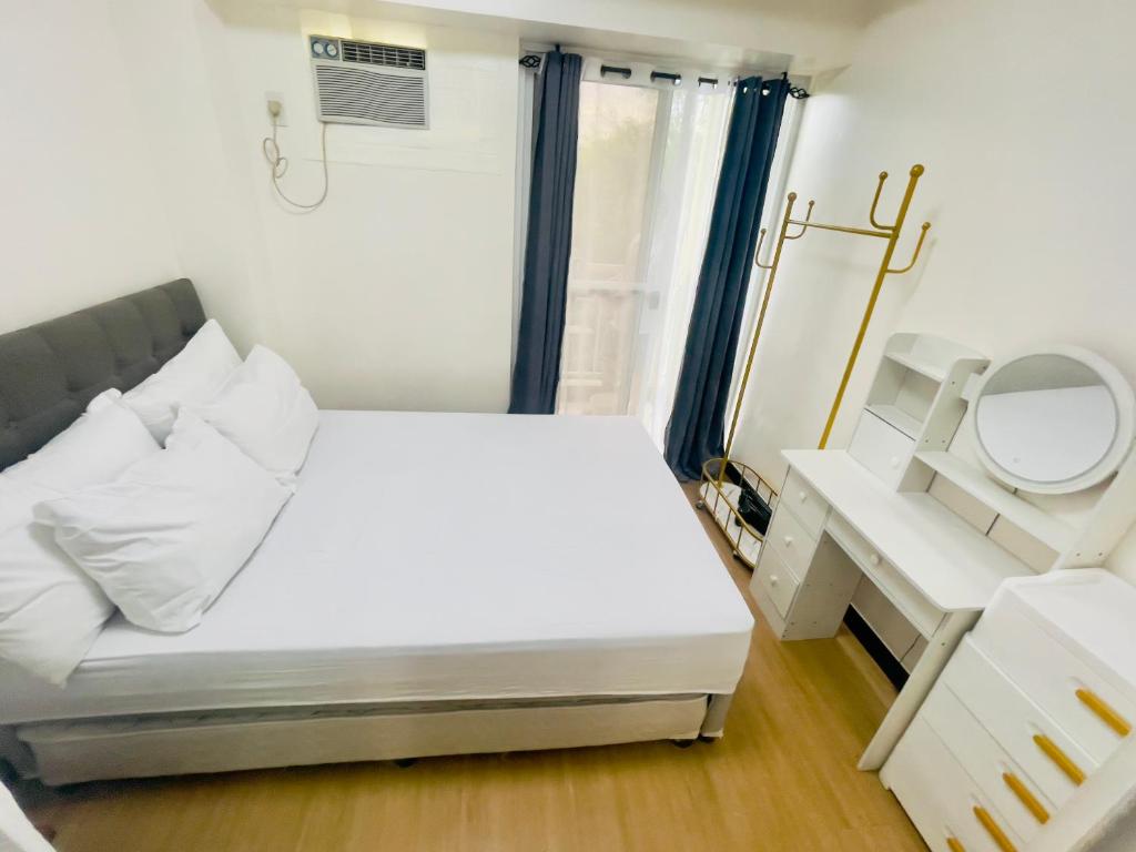 Dormitorio pequeño con cama y espejo en 1 Bedroom with Balcony, en Manila