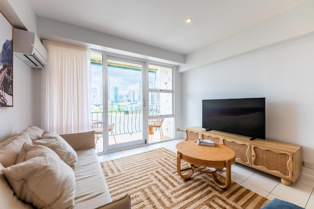 a living room with a couch and a tv and a table at Riverside 2 Bedroom apartment with parking in Brisbane