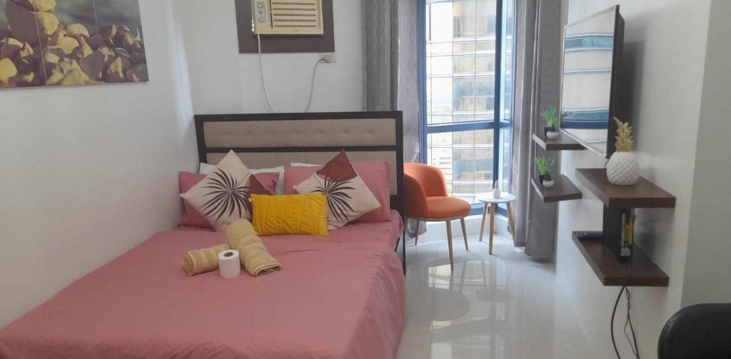 a bedroom with a pink bed with colorful pillows at Grand Riviera Suites, US Embassy Comfy, Affordable Studio in Roxas Blvd, Ermita Manila in Manila