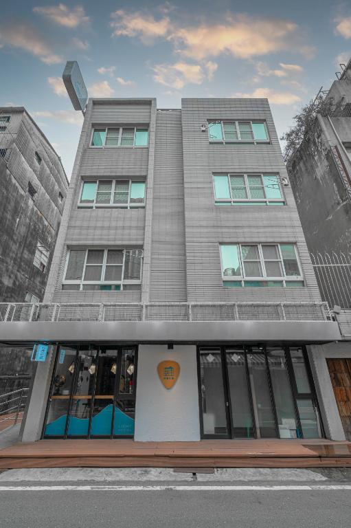 a tall gray building with windows on a street at Light Hostel in Chiayi City