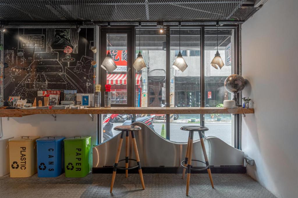 a bar with stools in front of a window at Light Hostel in Chiayi City