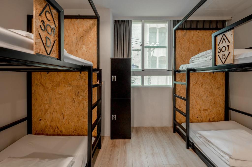 a dorm room with three bunk beds and a window at Light Hostel in Chiayi City