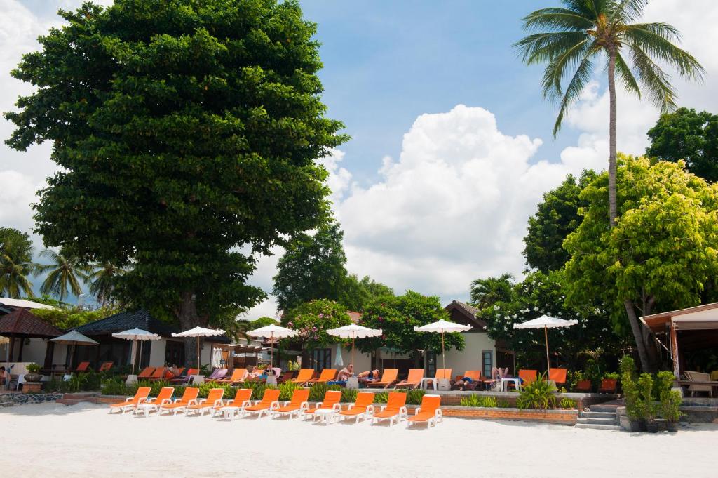 a group of chairs and umbrellas on a beach at Montien House - SHA Plus in Chaweng