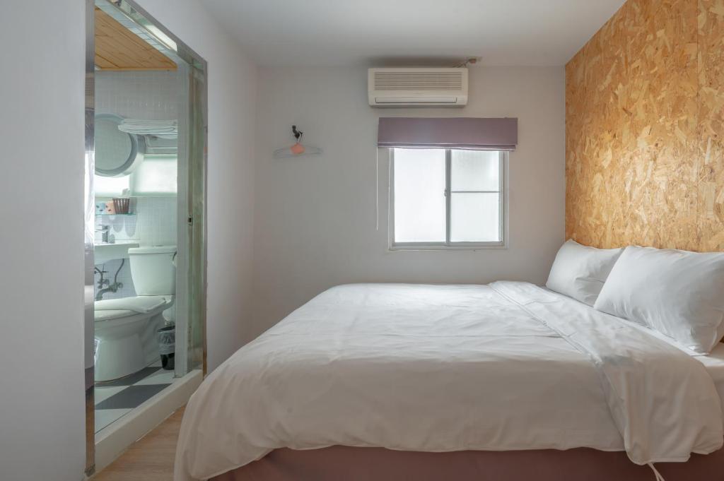 a bedroom with a large white bed and a bathroom at Light Hostel in Chiayi City