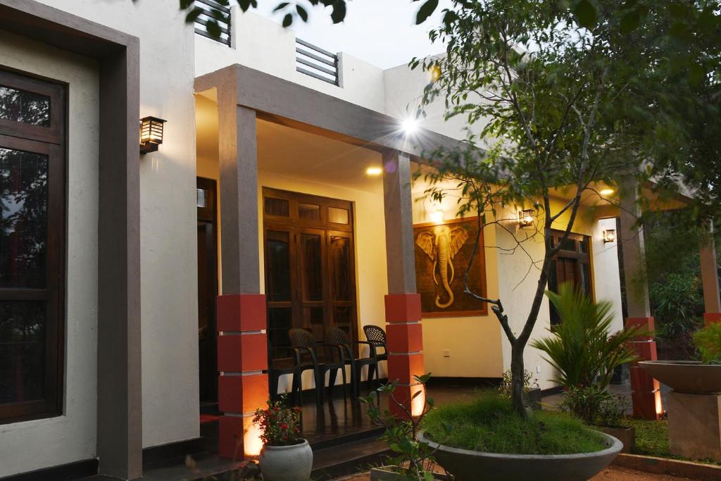 una casa con un porche delantero con un árbol en Leaf Dew Resort, en Anuradhapura