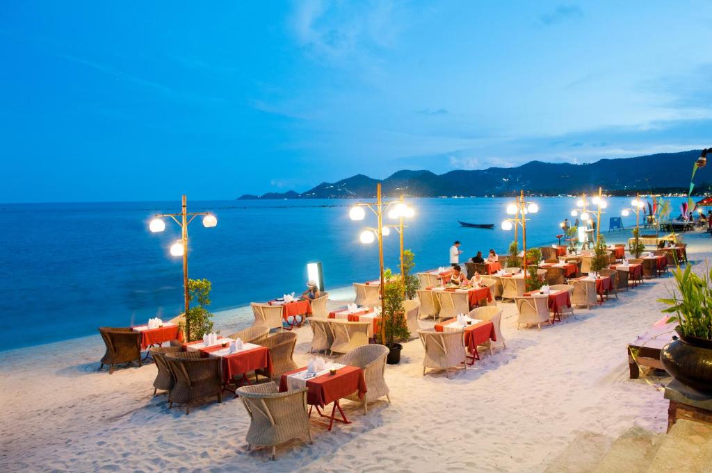 a restaurant on the beach with tables and chairs at Montien House - SHA Plus in Chaweng