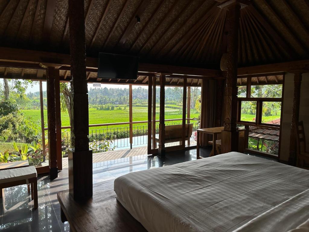 a bedroom with a bed and a view of a field at GRIYA KCB VILLA in Ubud