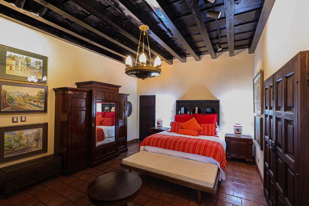 a bedroom with a bed with red sheets and a chandelier at Hotel Casa Bansley in Antigua Guatemala