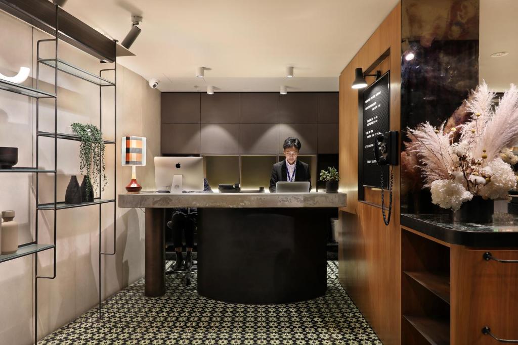 een man aan een bureau in een kamer met een laptop bij The Canvas Apartment Hotel in Melbourne