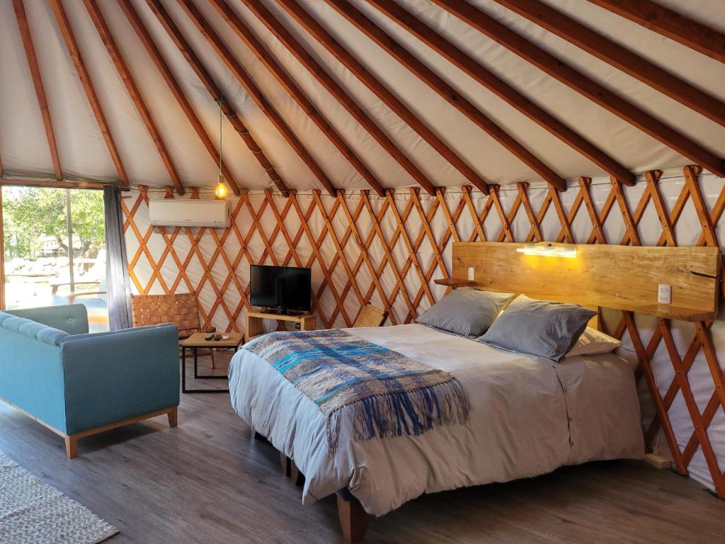 1 dormitorio con 1 cama y 1 silla en una yurta en Cabaña espectacular, con vista al río y hot tub privado, en Linares