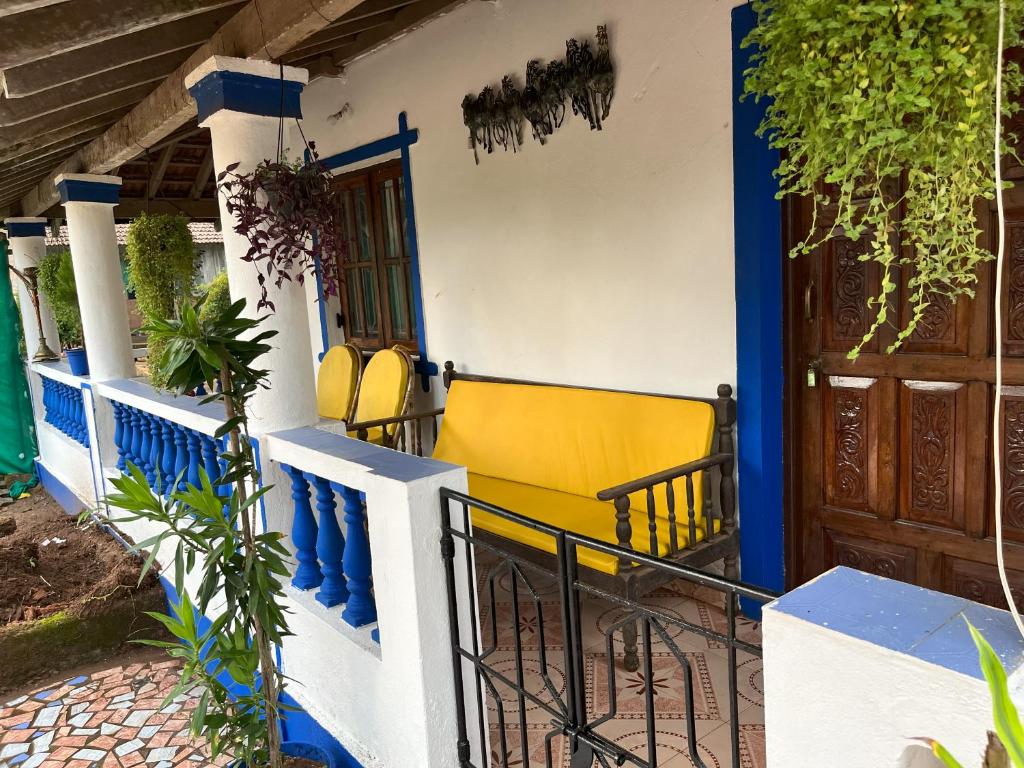 uma casa azul e branca com cadeiras amarelas no alpendre em Ales & Juli em Morjim