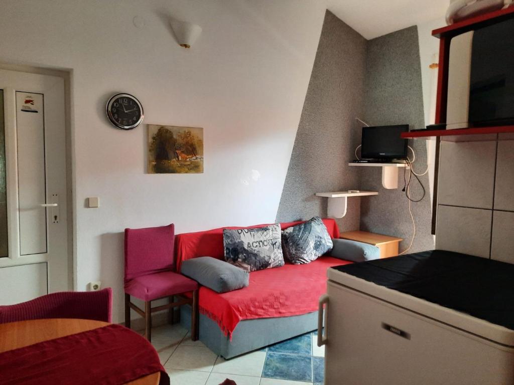 uma sala de estar com um sofá vermelho e uma cadeira vermelha em Apartments Visnja - 10 meters to the sandy beach em Nin