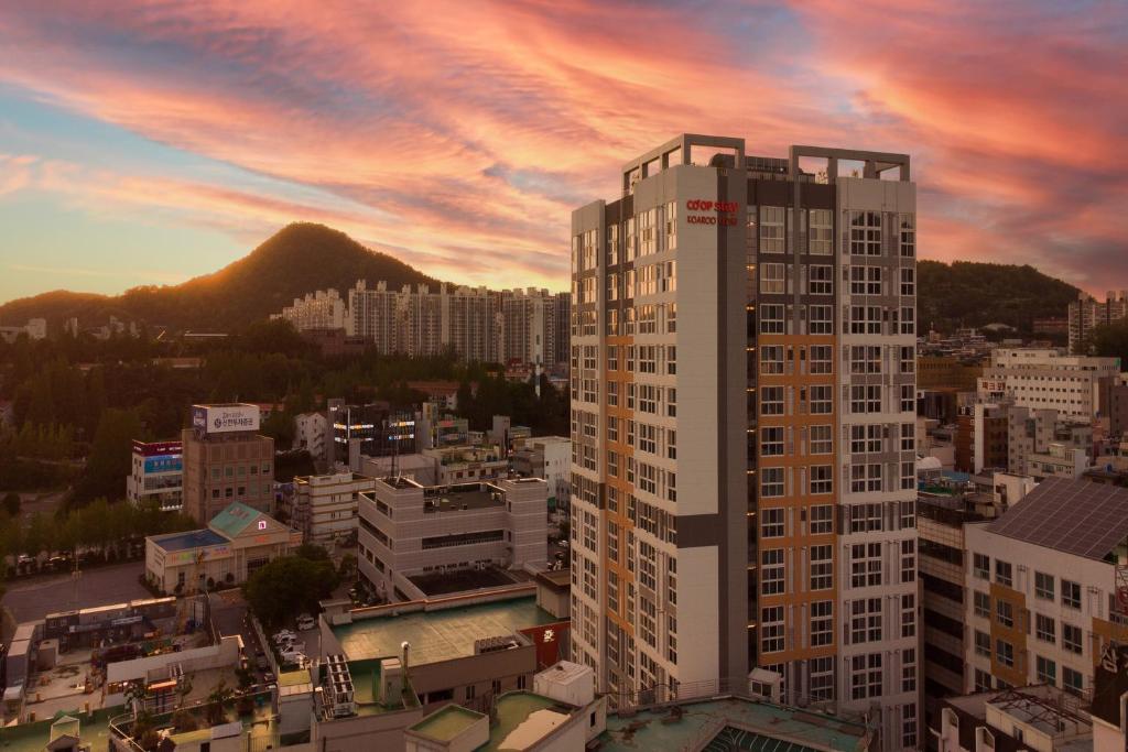 a tall building in a city at sunset at Coopstay Yeosu Hotel in Yeosu