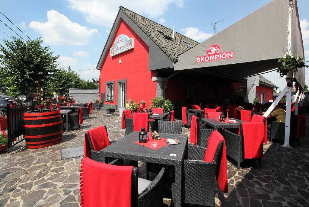 a red restaurant with tables and chairs in front of a building at Penzion Škorpión in Senec