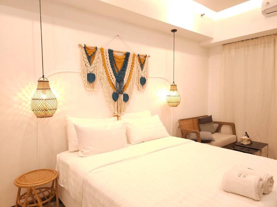 um quarto com uma cama branca e uma cadeira em Nagoya 名古屋 at Benson Apartment em Surabaya