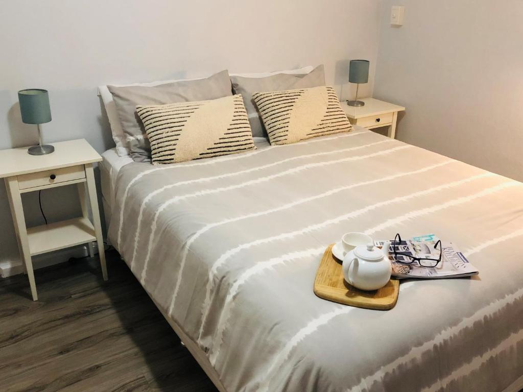 uma cama com uma bandeja com um bule de chá em API Middleton Beach Front Apartments Albany em Albany