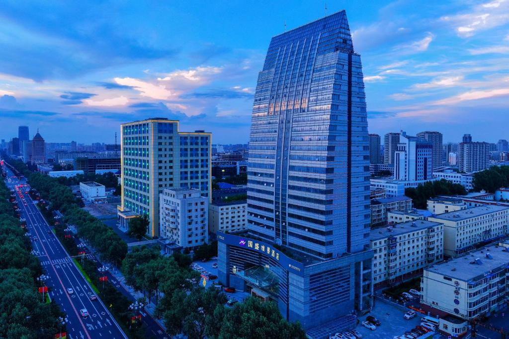 Blick auf ein hohes Gebäude in einer Stadt in der Unterkunft Metropark Changchun Guosheng Hotel in Changchun