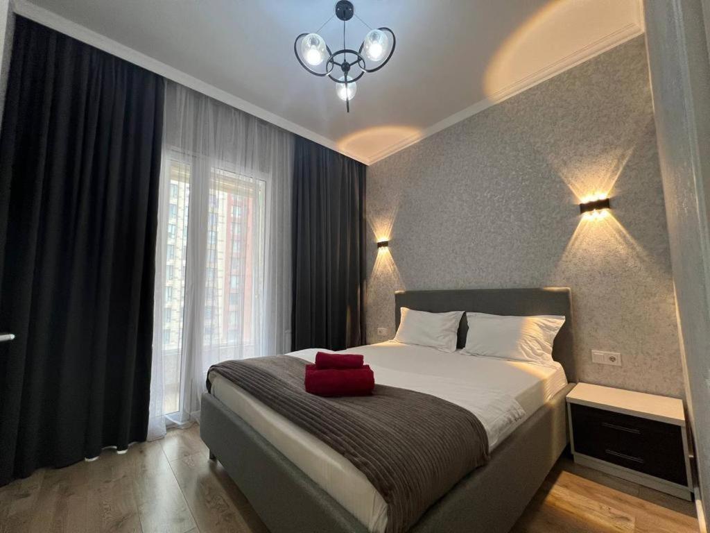 ein Schlafzimmer mit einem Bett, auf dem ein roter Gegenstand liegt in der Unterkunft Уютные апартаменты в элитном комплексе in Almaty